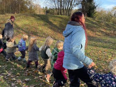 Voksne og børn på række på legepladsen